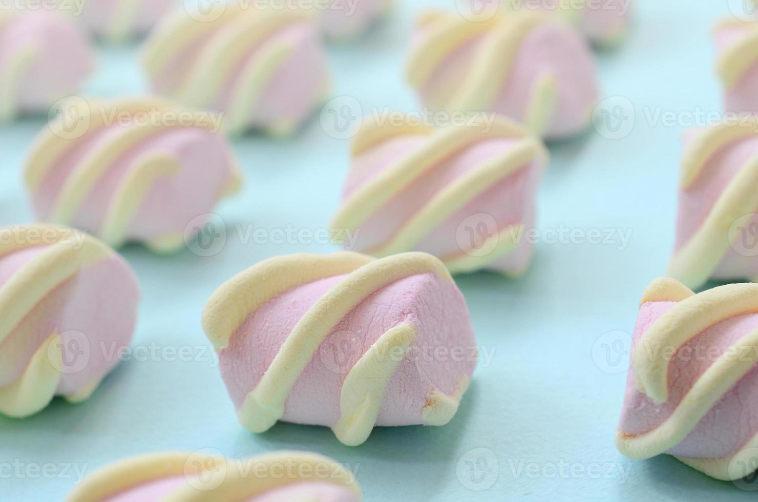 Colorful marshmallow laid out on blue paper background. pastel creative textured pattern. Perspective macro shot photo