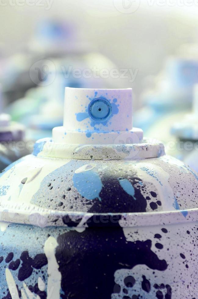 A lot of dirty and used aerosol cans of bright blue paint. Macro photograph with shallow depth of field. Selective focus on the spray nozzle photo