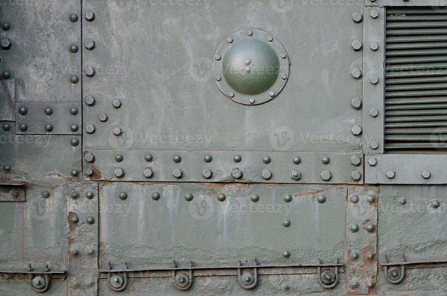 Texture of tank side wall, made of metal and reinforced with a multitude of bolts and rivets photo