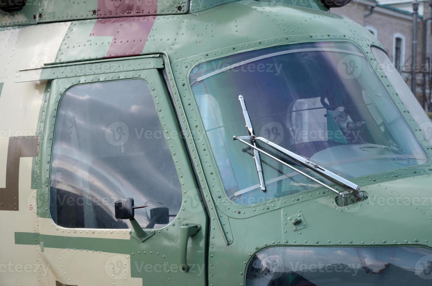 Helicopter cabin fragment close up. Camouflage aircraft fuselage and bulletproof glass photo