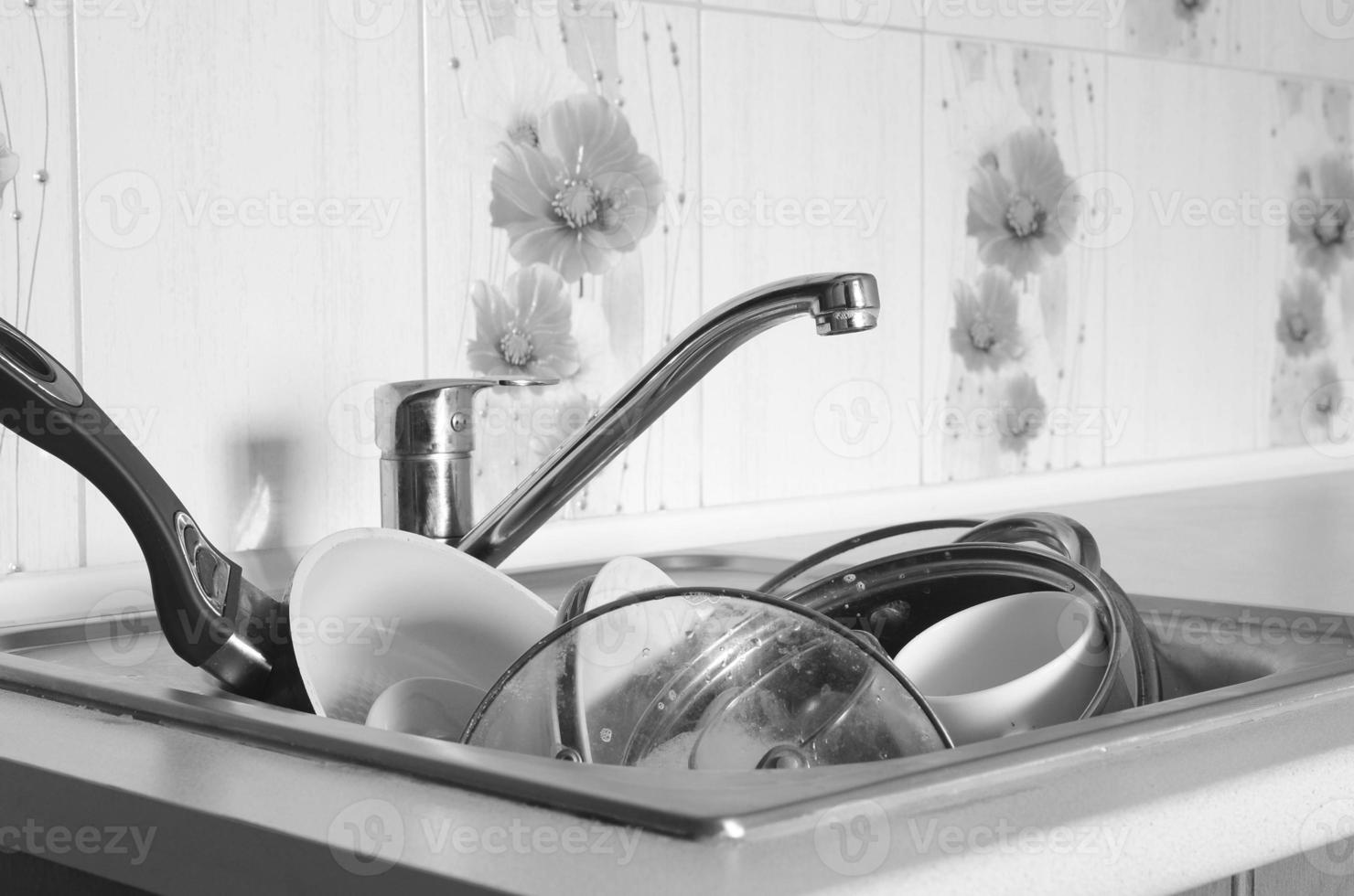 Dirty dishes and unwashed kitchen appliances filled kitchen sink photo