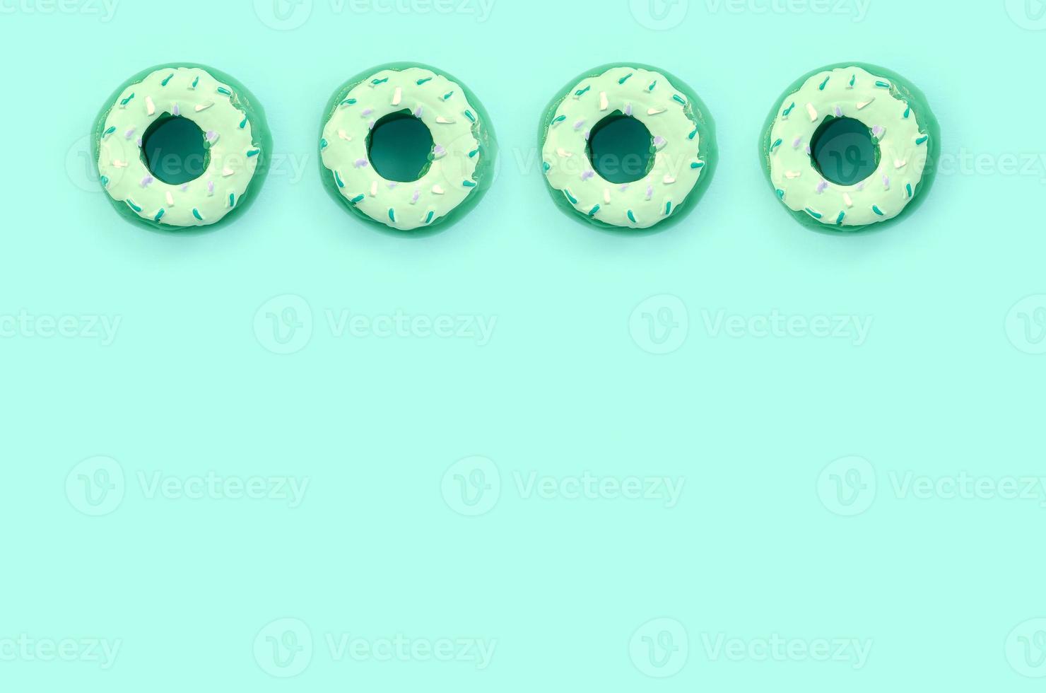 Many small plastic donuts lies on a pastel colorful background. Flat lay minimal pattern. Top view photo