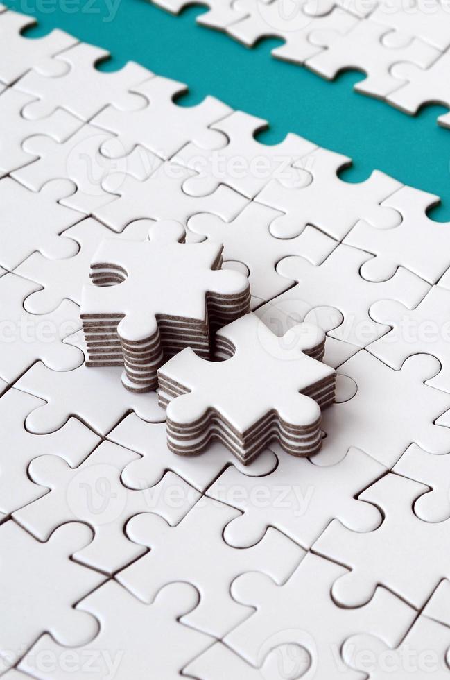 The blue path is laid on the platform of a white folded jigsaw puzzle. The missing elements of the puzzle are stacked nearby. Texture image with space for text photo