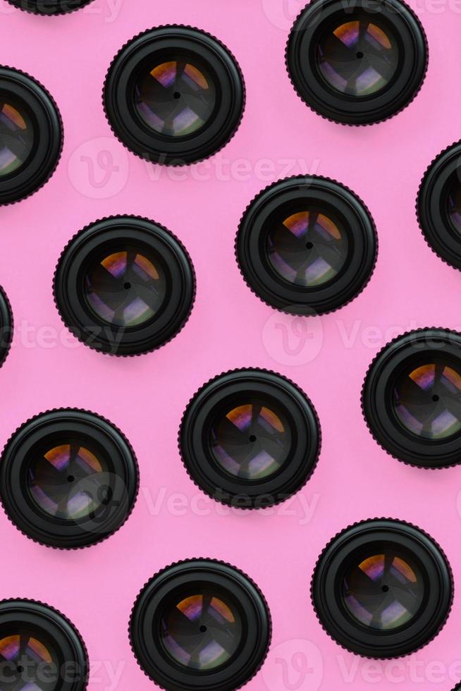 A few camera lenses with a closed aperture lie on texture background of fashion pastel pink color paper in minimal concept. Abstract trendy pattern photo