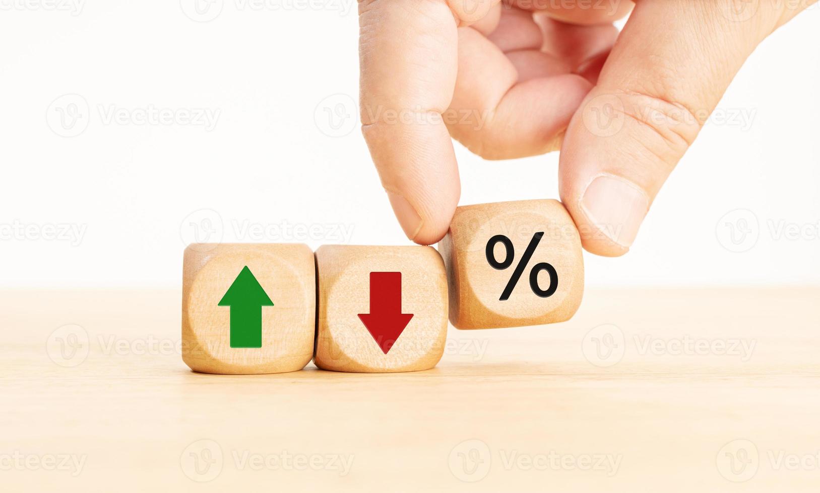 Stock market, Business and finance concept. Hand holding a Wooden block with percent, up or down arrow icons photo