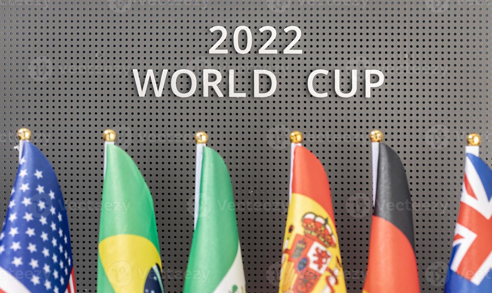 2022 World Cup text on a board and group of different flags of participating countries photo