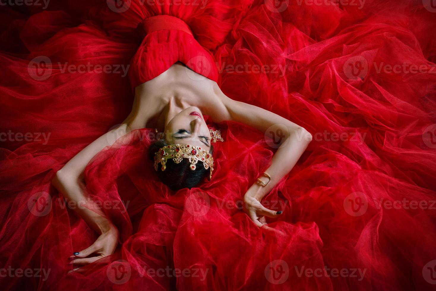 bella mujer con vestido rojo largo y corona real interior foto