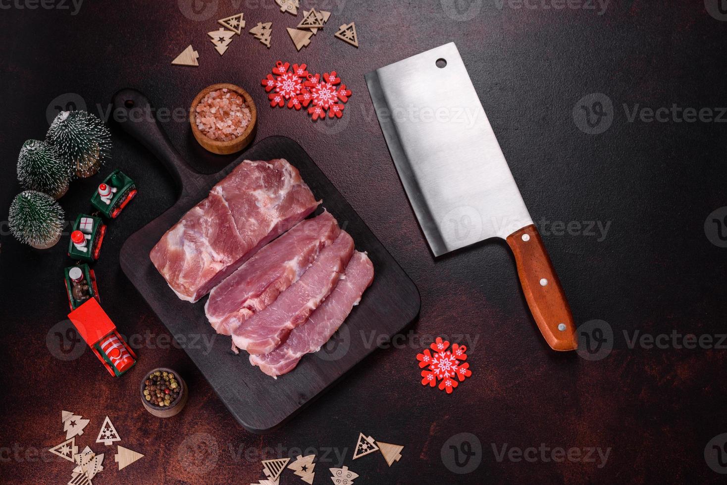 Fresh piece of raw pork with spices, salt and herbs on a wooden cutting board photo