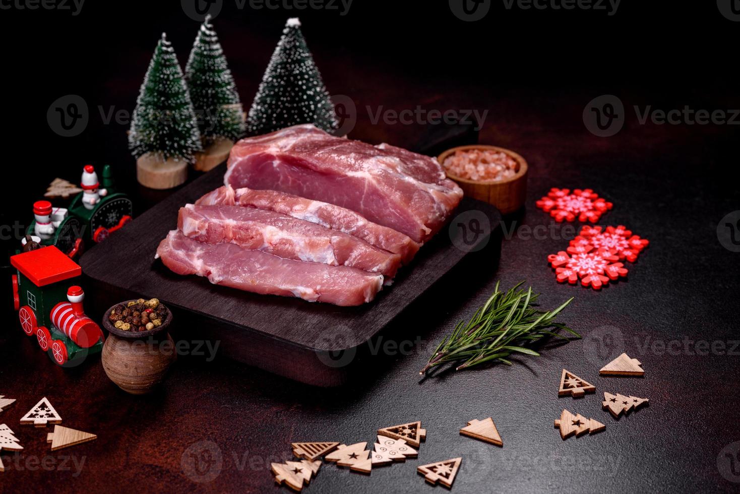 Fresh piece of raw pork with spices, salt and herbs on a wooden cutting board photo