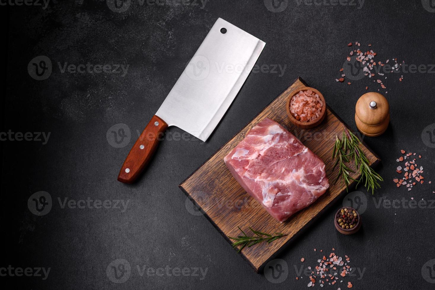 Fresh piece of raw pork with spices, salt and herbs on a wooden cutting board photo