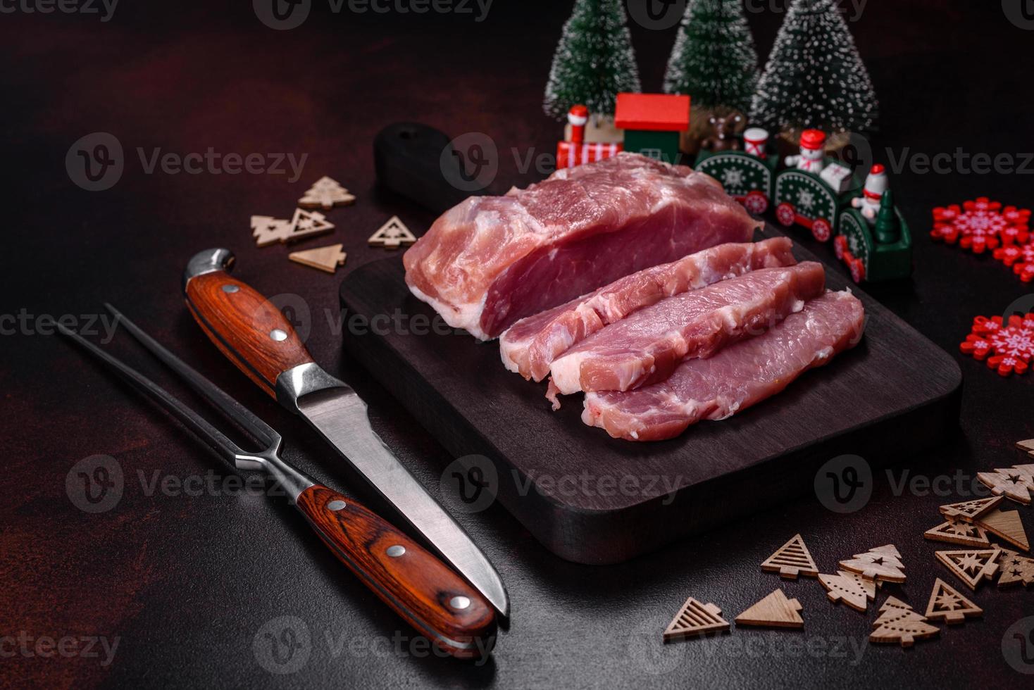 Fresh piece of raw pork with spices, salt and herbs on a wooden cutting board photo