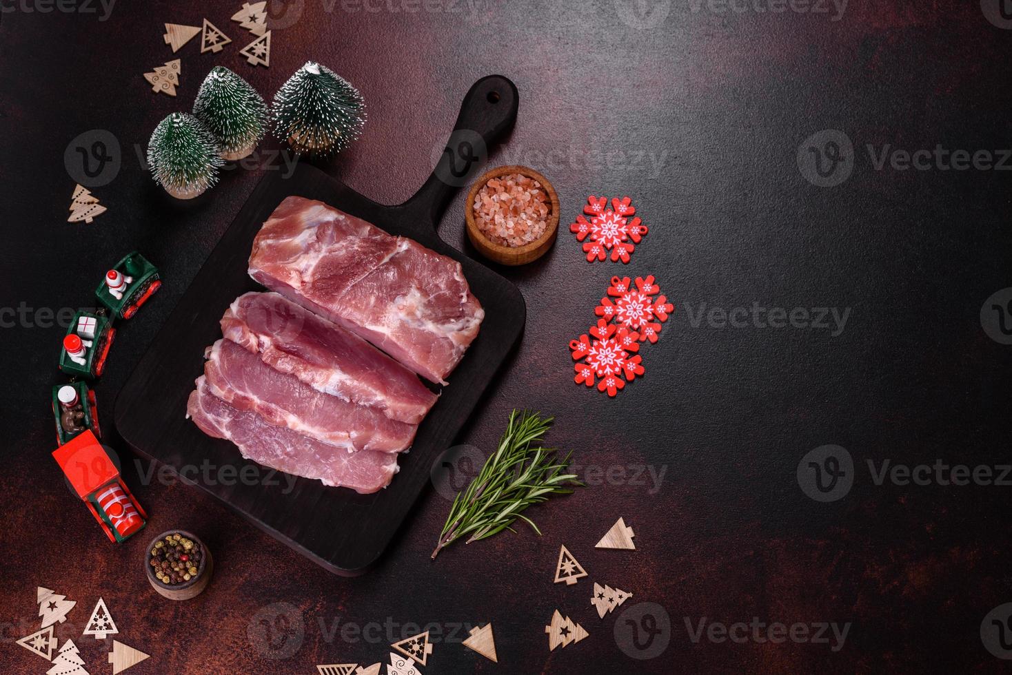 pieza fresca de cerdo crudo con especias, sal y hierbas en una tabla de cortar de madera foto