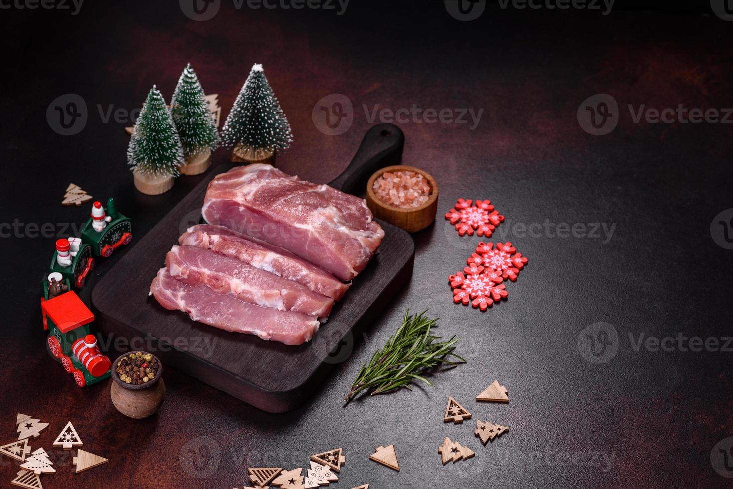 Fresh piece of raw pork with spices, salt and herbs on a wooden cutting board photo