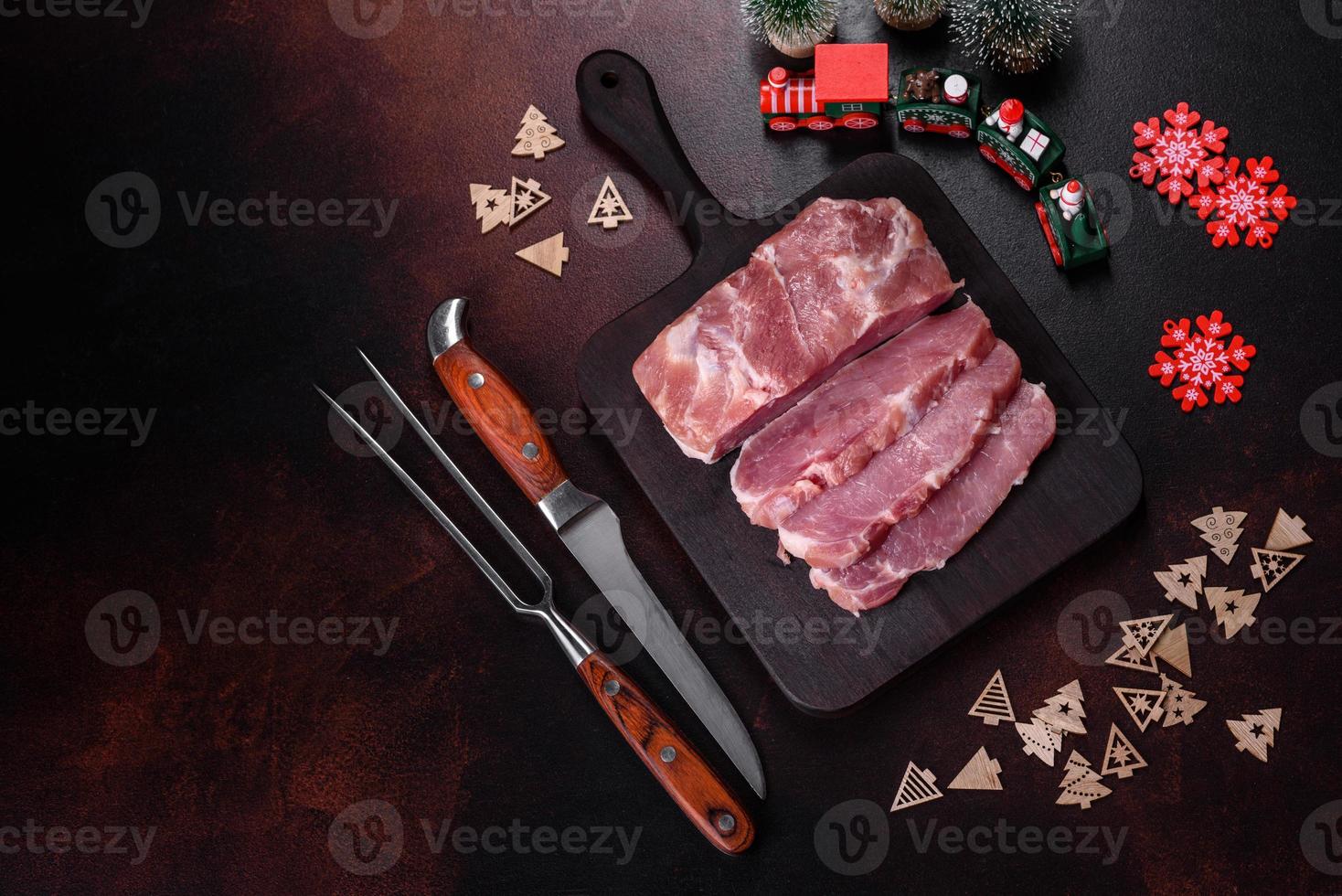 pieza fresca de cerdo crudo con especias, sal y hierbas en una tabla de cortar de madera foto