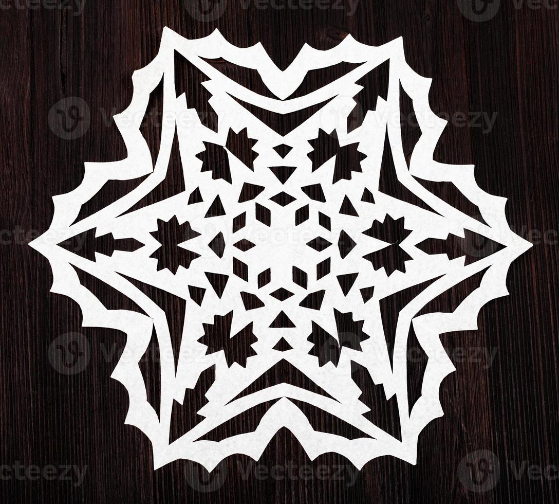 snowflake cut out of paper on dark brown board photo