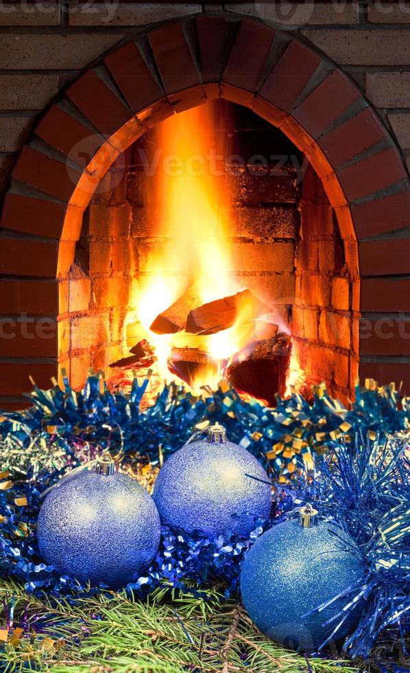 blue Christmas balls on spruce tree and fireplace photo