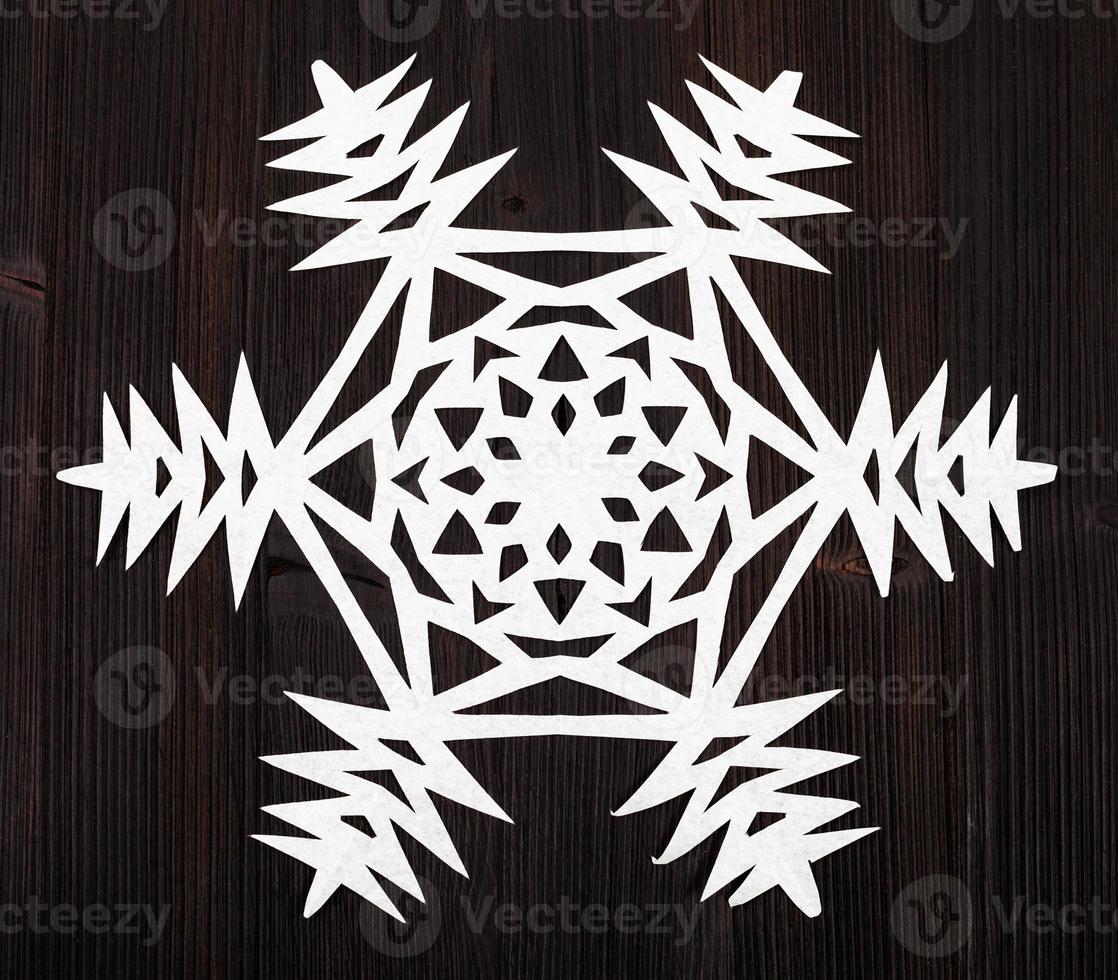 snowflake cut out of paper on dark brown surface photo