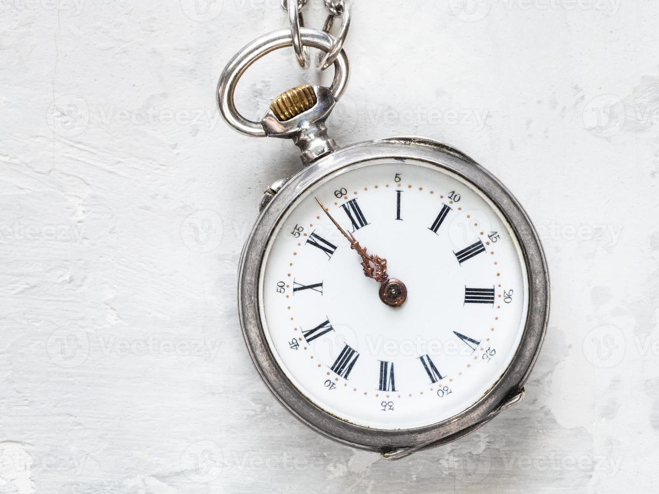two minutes to twelve on antique watch on concrete photo