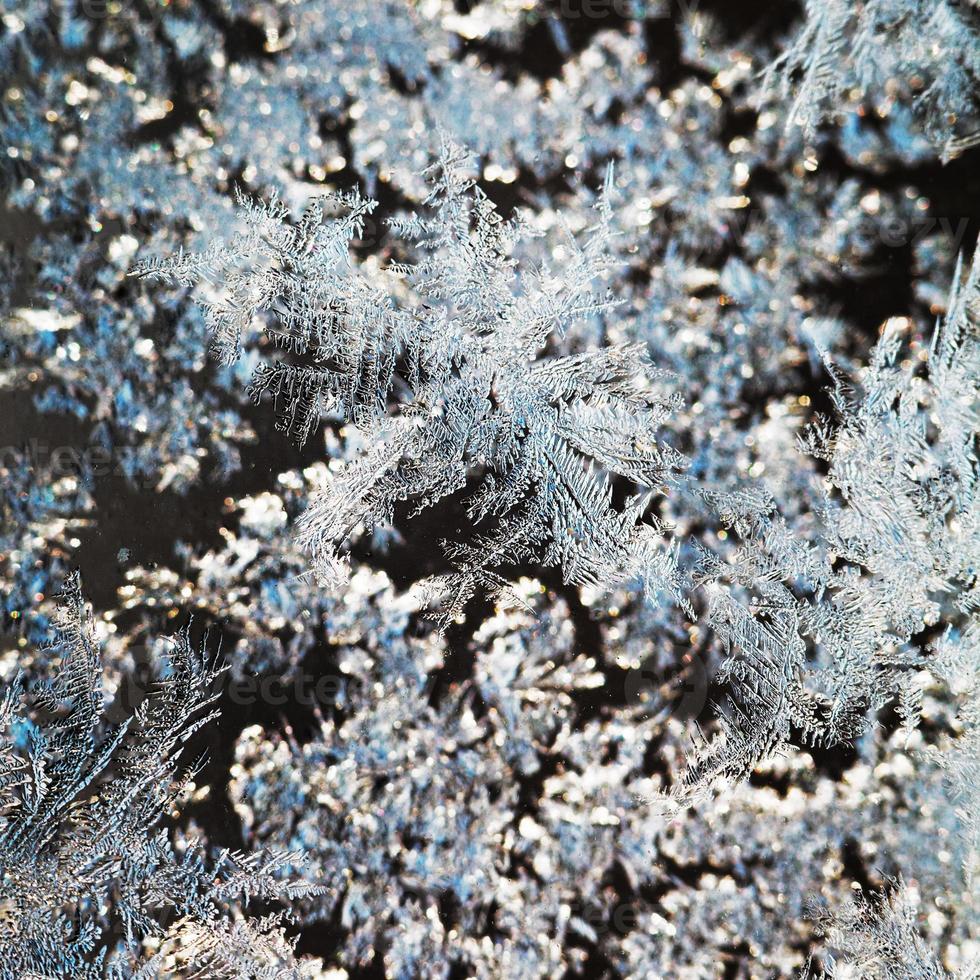 copos de nieve y patrón de escarcha en el vidrio de cerca foto