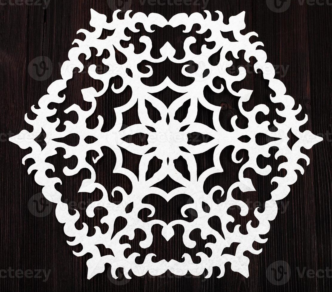 snowflake cut out of paper on dark brown table photo