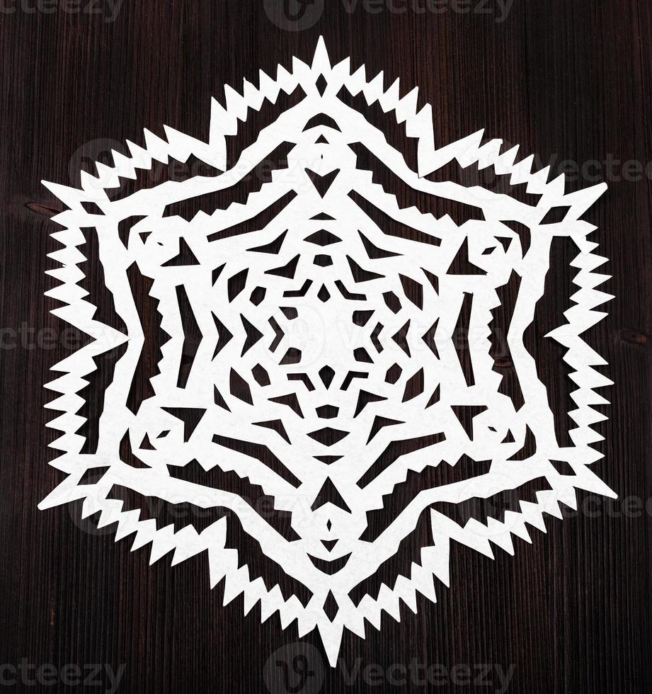 snowflake cut out of paper on dark brown plank photo