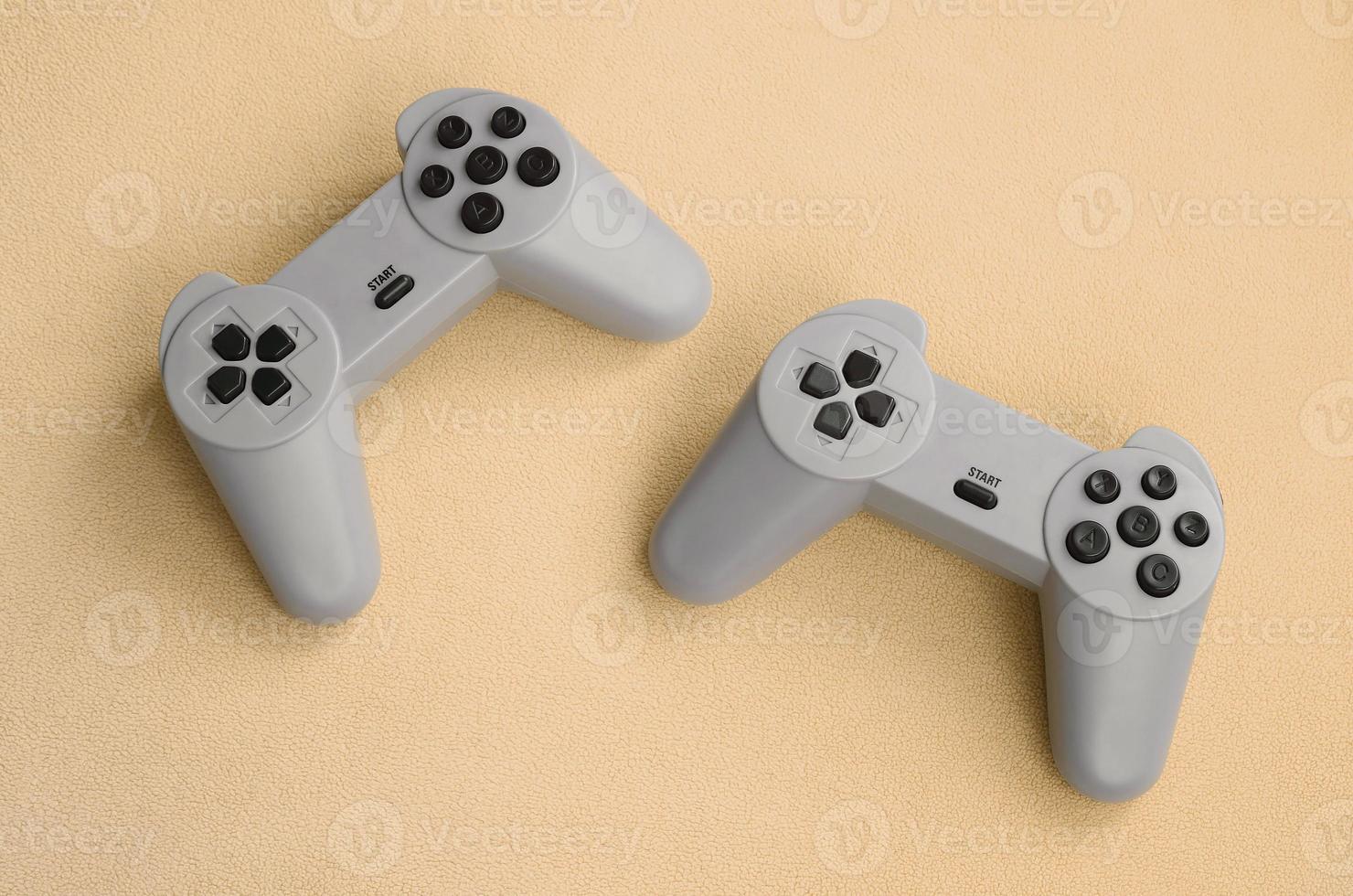 Playing games concept. Two pad joysticks lies on the blanket of furry orange fleece fabric. Controllers for video games on a background texture of light orange soft plush fleece material photo