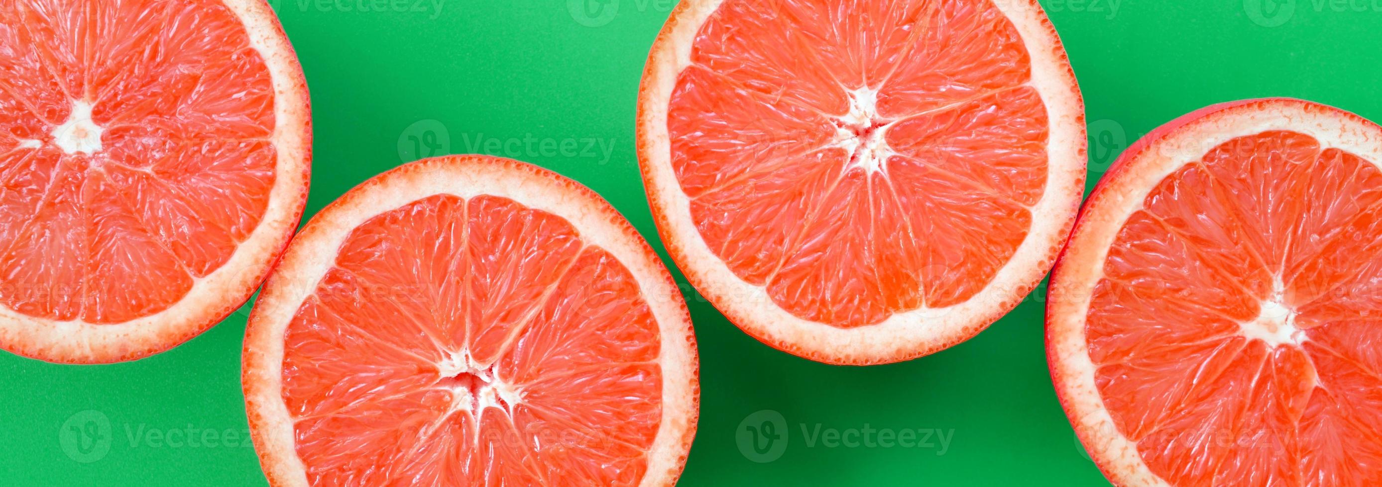 vista superior de varias rodajas de pomelo sobre fondo brillante en color verde. una imagen de textura cítrica saturada foto