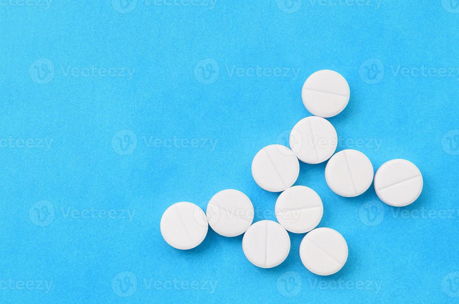Several white tablets lie on a bright blue background in the form of a bacterium. Background image on medicine and pharmaceutical topics photo