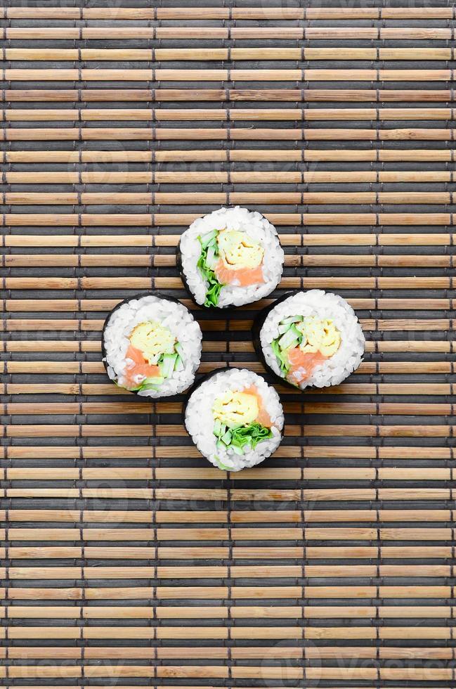 Sushi rolls lies on a bamboo straw serwing mat. Traditional Asian food. Top view. Flat lay minimalism shot with copy space photo