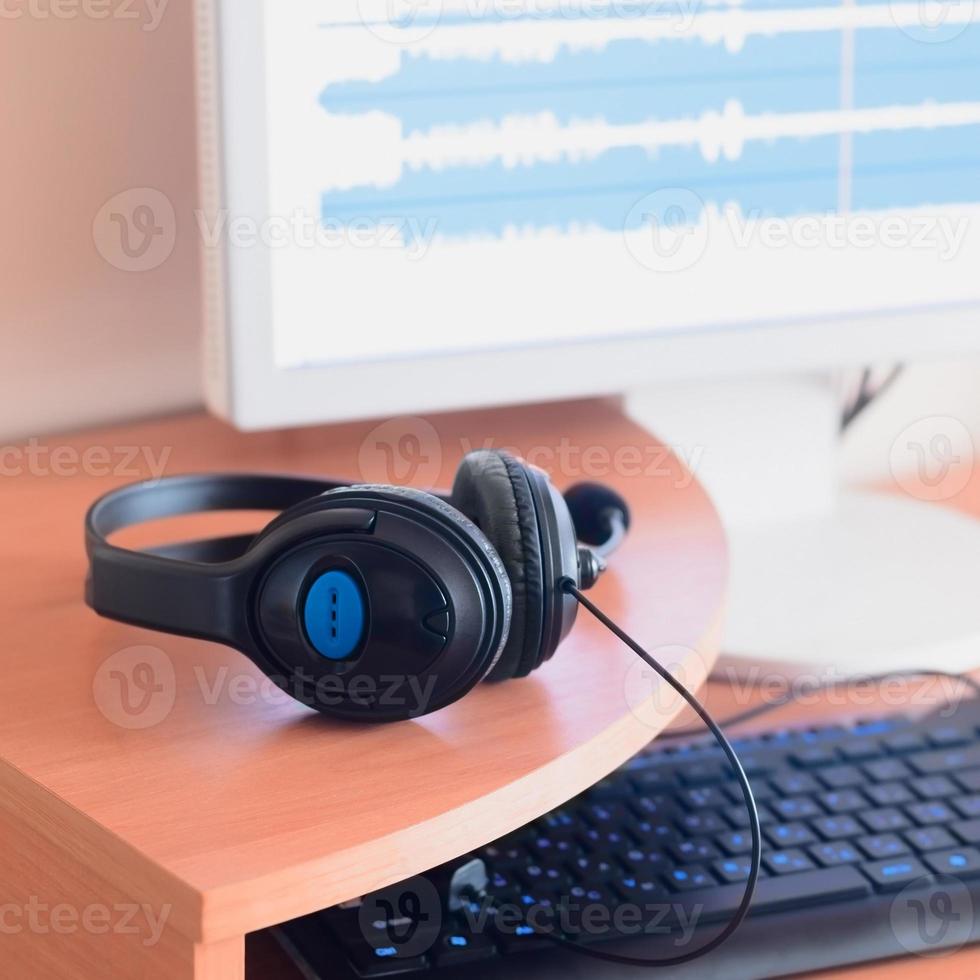 Big black headphones lie on the wooden desktop of the sound designer photo