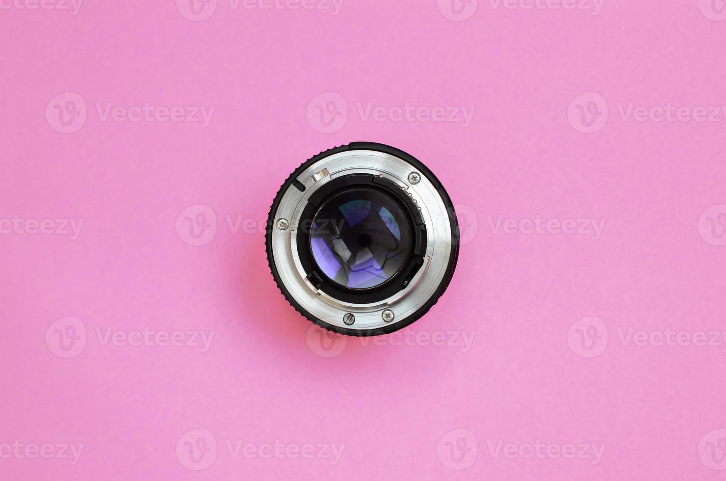 Camera lens with a closed aperture lie on texture background of fashion pastel pink color paper in minimal concept photo