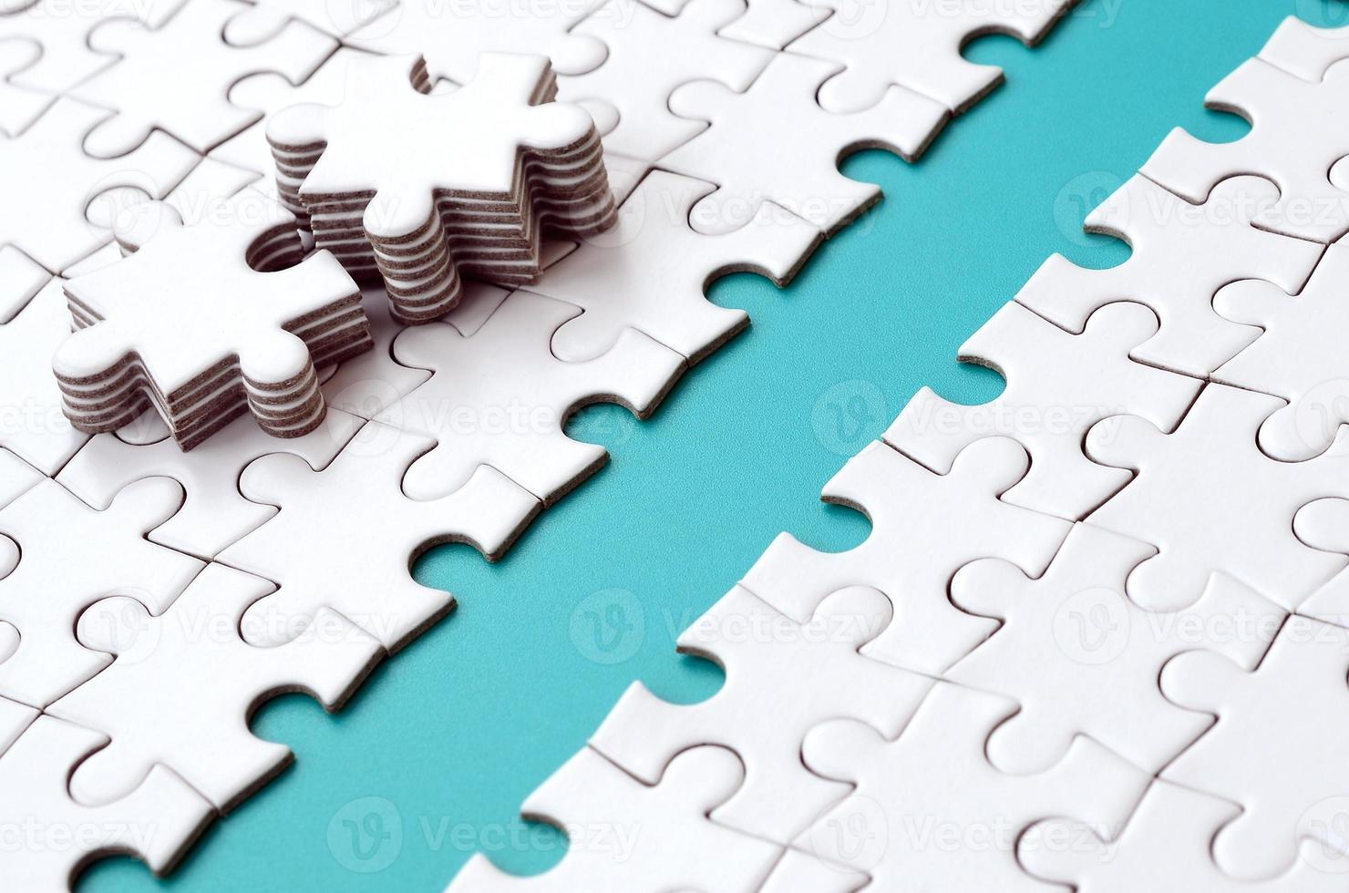 The blue path is laid on the platform of a white folded jigsaw puzzle. The missing elements of the puzzle are stacked nearby. Texture image with space for text photo