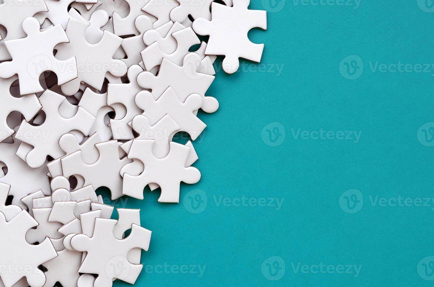 A pile of uncombed elements of a white jigsaw puzzle lies on the background of a blue surface. Texture photo with copy space for text