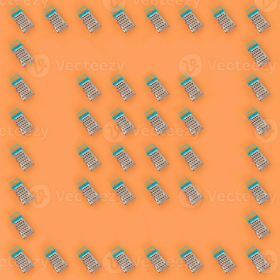 Small stainless steel graters lies on a pastel colored paper. Kitchen accessories. Tools for cooking. Flat lay top view photo