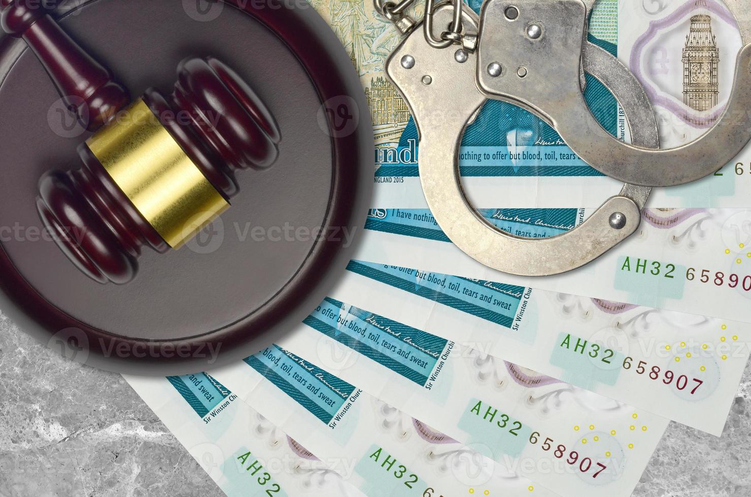 5 British pounds bills and judge hammer with police handcuffs on court desk. Concept of judicial trial or bribery. Tax avoidance photo