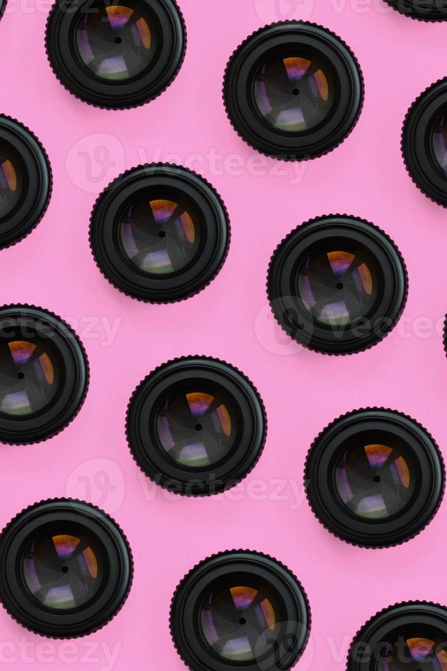 A few camera lenses with a closed aperture lie on texture background of fashion pastel pink color paper in minimal concept. Abstract trendy pattern photo