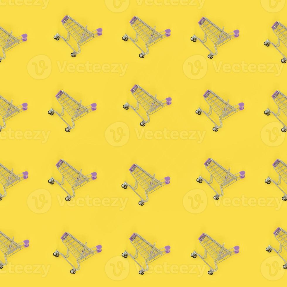 Shopping addiction, shopping lover or shopaholic concept. Many small empty shopping carts perform a pattern on a pastel colored paper background. Flat lay composition, top view photo