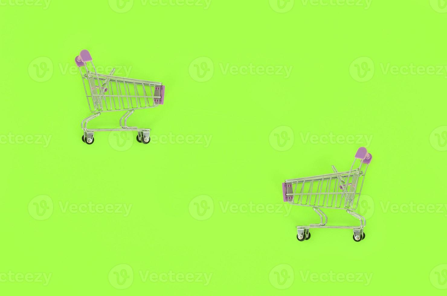 Shopping addiction, shopping lover or shopaholic concept. Small empty shopping cart lies on a pastel colored paper background. Flat lay minimal composition, top view photo