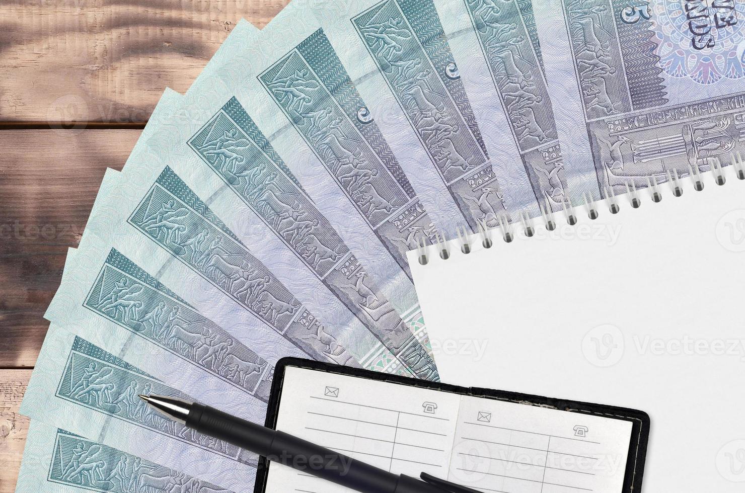 Abanico de billetes de 5 libras egipcias y bloc de notas con libreta de contactos y bolígrafo negro. concepto de planificación financiera y estrategia empresarial foto