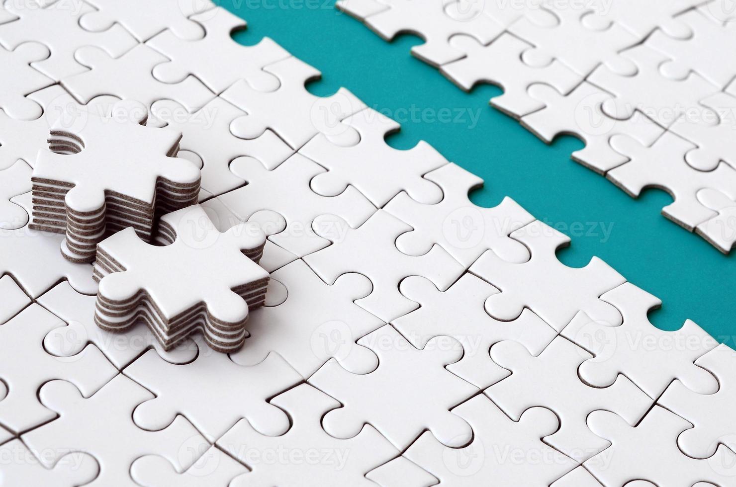 The blue path is laid on the platform of a white folded jigsaw puzzle. The missing elements of the puzzle are stacked nearby. Texture image with space for text photo