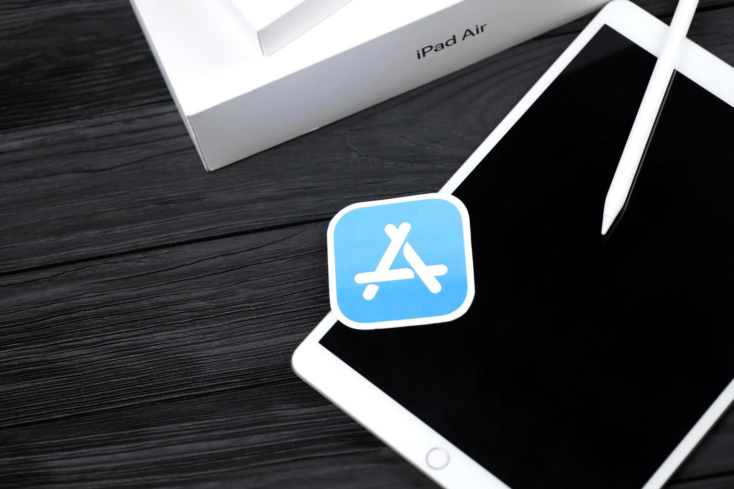 KHARKIV, UKRAINE - JANUARY 27, 2022 Brand new Apple iPad and Apple Pencil and blue app store logo on black background. Apple Inc. is an American technology company photo