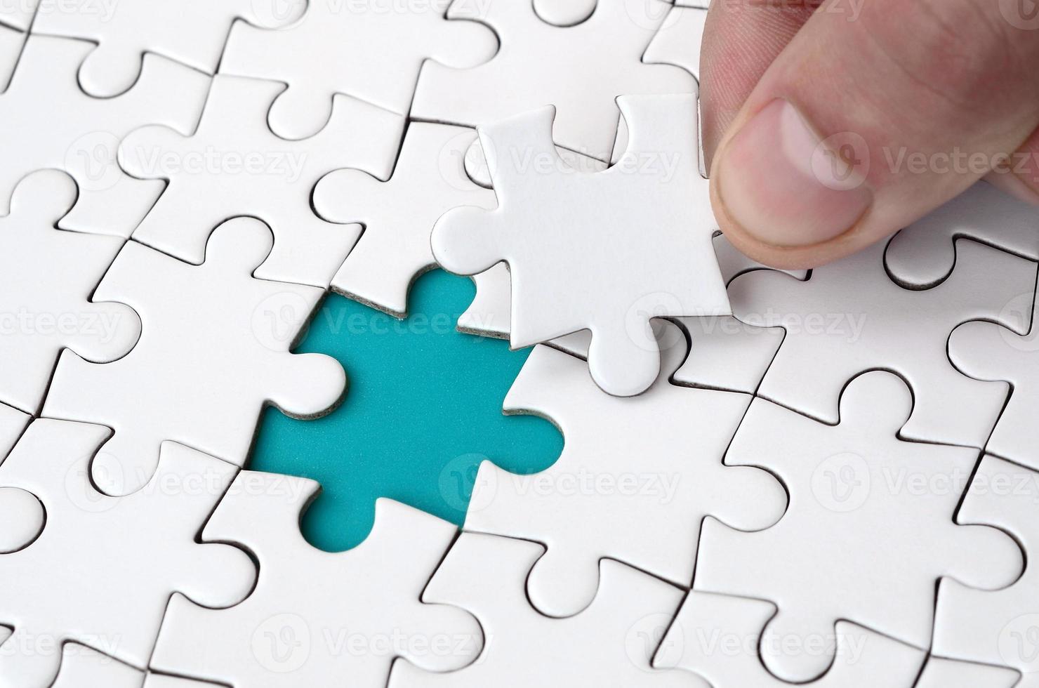 The human hand fills the last missing elements of the surface from the jigsaw puzzle. The concept of the completion of the initiated cases photo
