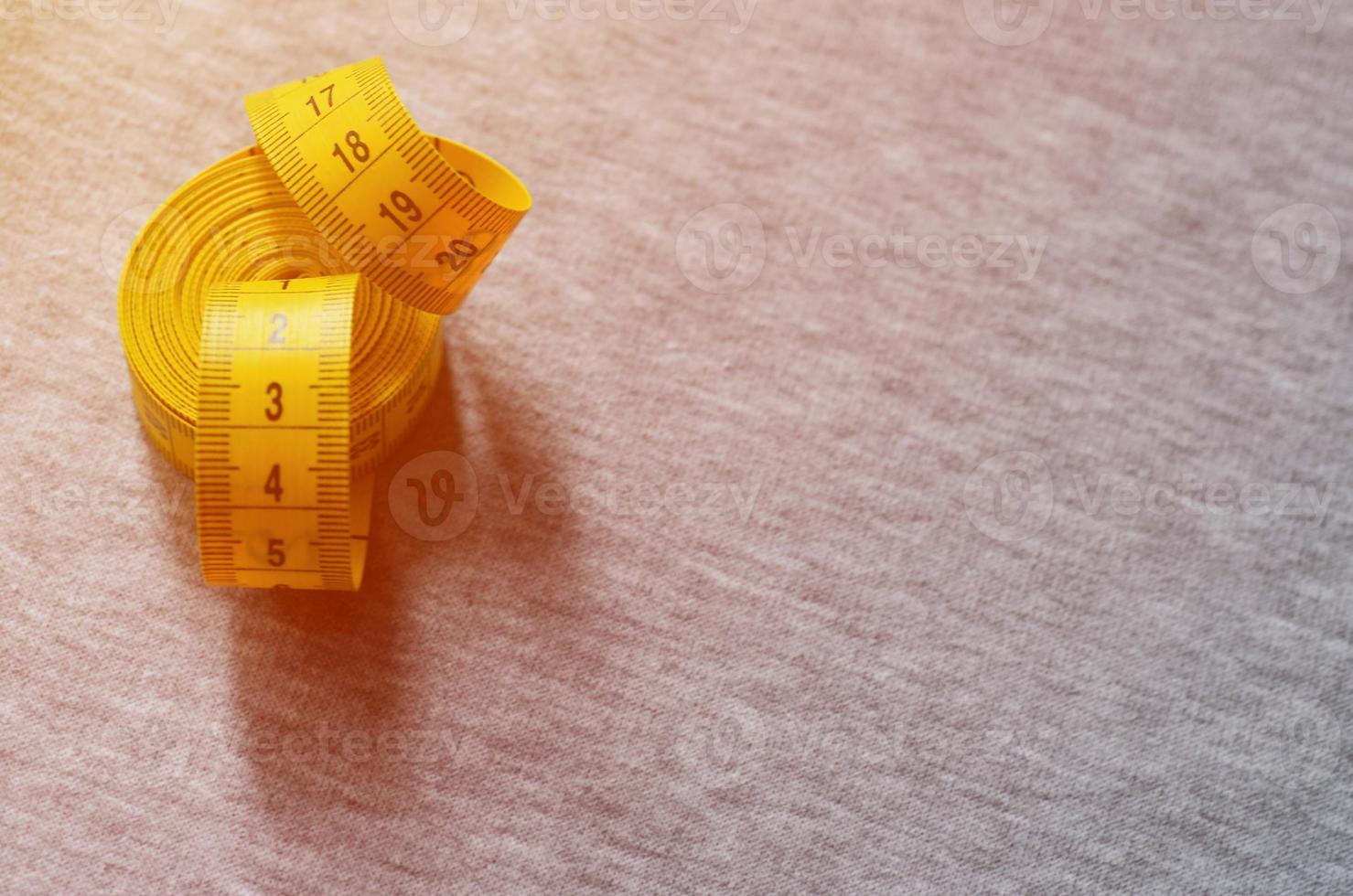 Yellow measuring tape lies on a gray knitted fabric photo