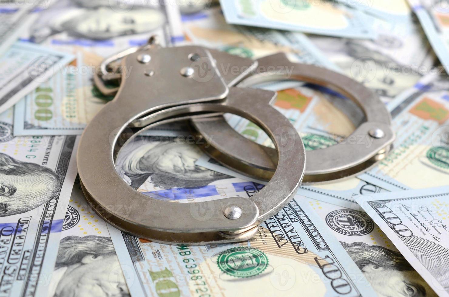 Silver police handcuffs lies on a many dollar bills photo