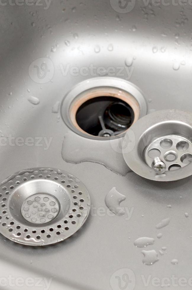 Silvery kitchen sink with a disassembled protective filter during the repair process photo