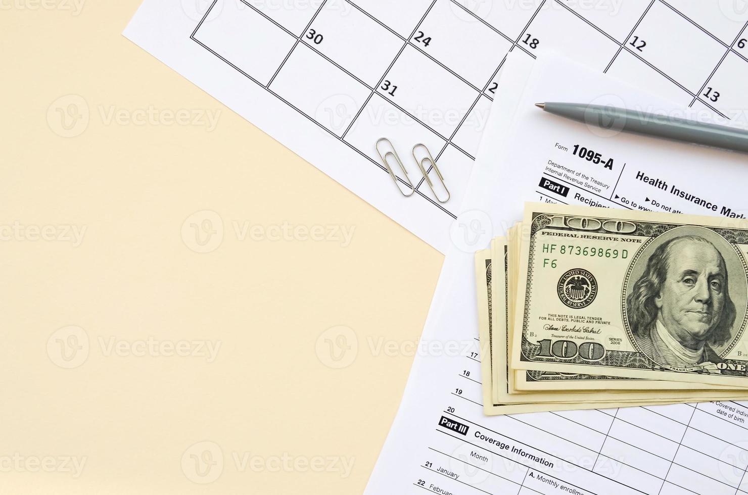 IRS Form 1095-A Health Insurance Marketplace Statement tax blank lies with pen and many hundred dollar bills on calendar page photo