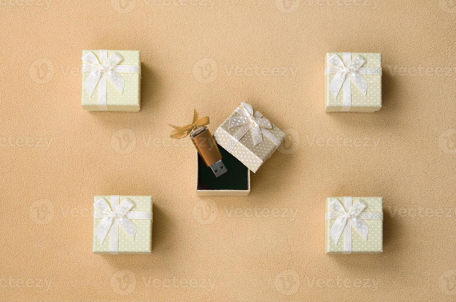 Orange usb flash memory card with a bow lies in a small gift box with a small bow on a blanket of soft and furry light orange fleece fabric. Classic fashion gift memory card design photo