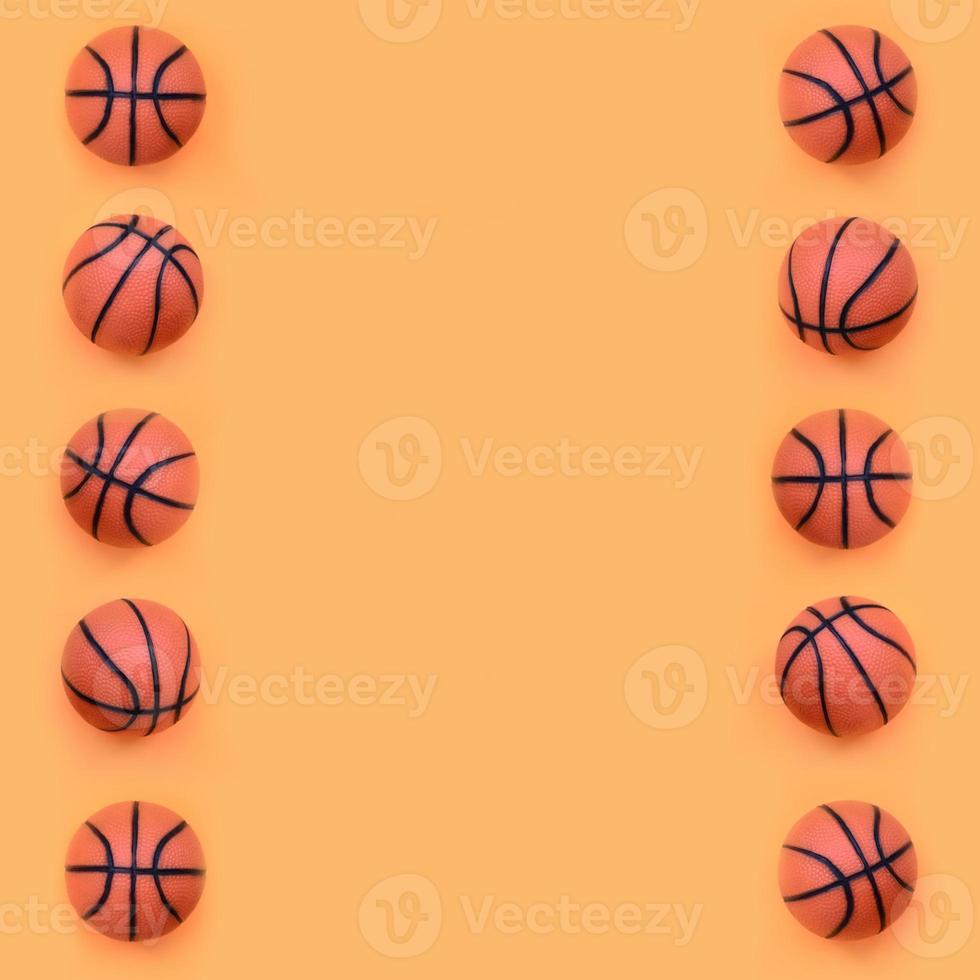 Many small orange balls for basketball sport game lies on texture background of fashion pastel orange color paper in minimal concept photo