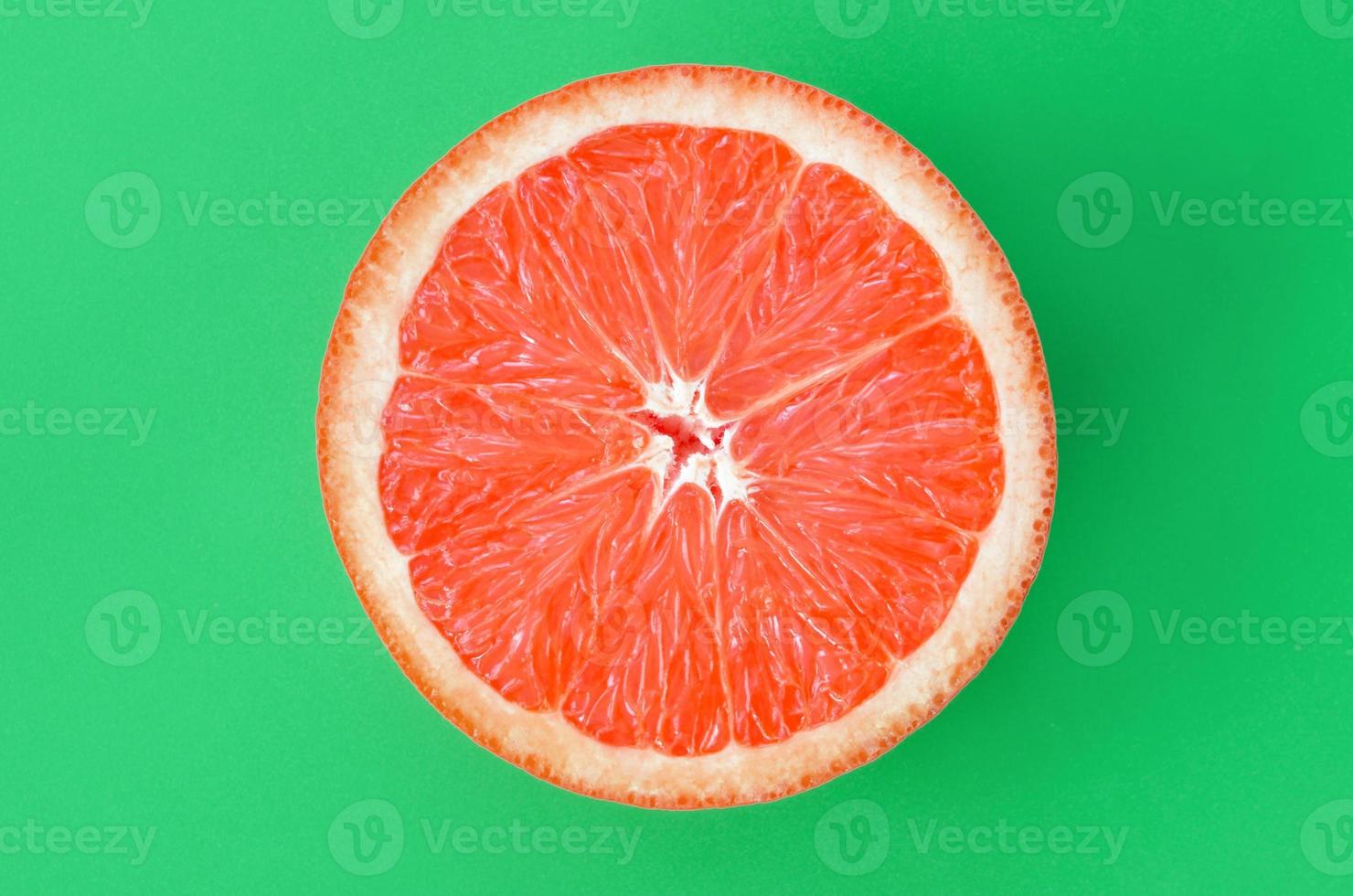 Top view of an one grapefruit slice on bright background in green color. A saturated citrus texture image photo