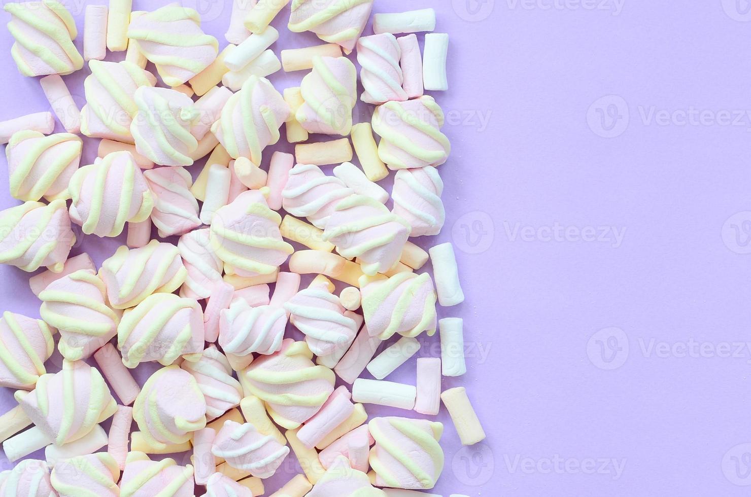 Colorful marshmallow laid out on violet paper background. pastel creative texture. minimal photo